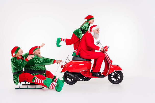 Portrait of attractive cheerful friends riding motor bike carrying sledge newyear isolated over white color background - Fotoğraf, Görsel