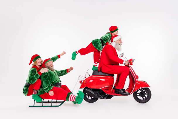 Portrait of attractive funny cheerful friends riding motor bike carrying sledge day holly jolly isolated over white color background - Zdjęcie, obraz