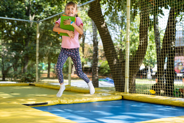 Tyttö kirjoja hypätä trampoliini - Valokuva, kuva