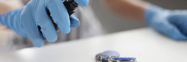 Muž v gumových ochranných rukavicích foukání sprej s antiseptikem na svazek klíčů detailní up - Fotografie, Obrázek