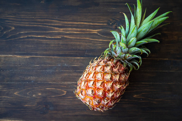 single whole pineapple on a wooden background. - Foto, Bild