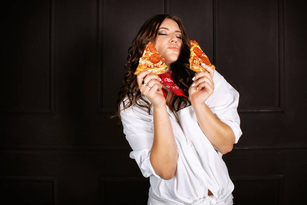 Красивая женщина пьет красное вино и ест пиццу. - Фото, изображение