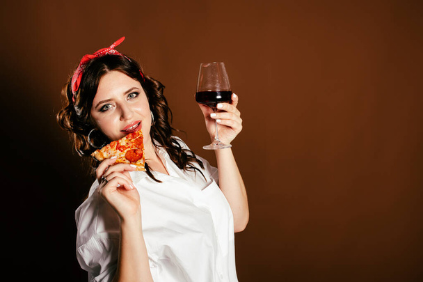 Beautiful woman drinks red wine and eats pizza. - Фото, изображение