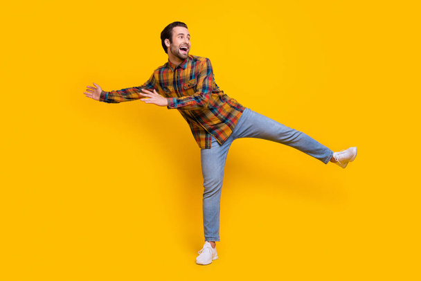 Full body photo of cool brunet young guy dance wear shirt jeans sneakers isolated on yellow background - Foto, afbeelding