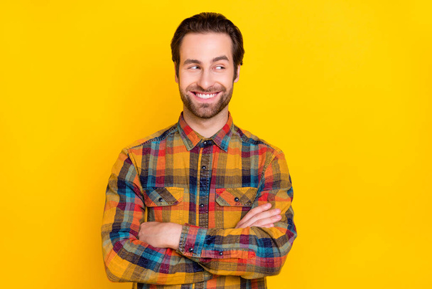Photo of confident pretty young guy dressed checkered shirt arms crossed looking empty space smiling isolated yellow color background - Foto, Imagen