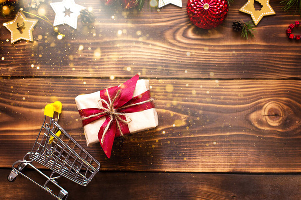Christmas flat lay on the theme of shopping, buying gifts for the new year. Black Friday, sale, decor of stars, spruce branches, ball, beads, garlands, cones on a wooden background. Space for text - 写真・画像