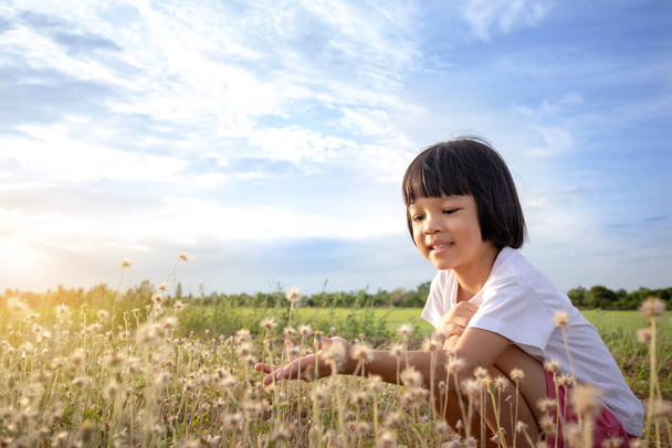 Thajské asijské dítě dívka, věk 4 až 6 let, roztomilý obličej, hraní venku. Na tváři měl šťastný úsměv. Pozadí jsou zelená pole a modrá obloha. Je to nádherná příroda na dovolené.. - Fotografie, Obrázek