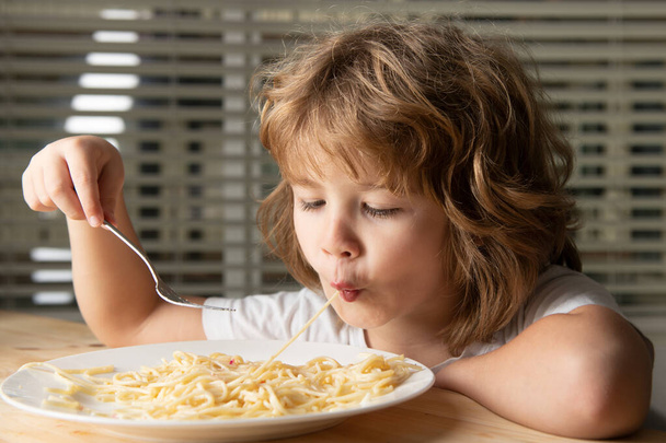 Close up head shot of child eating pasta, spaghetti. Kids face, little boy portrait. - 写真・画像