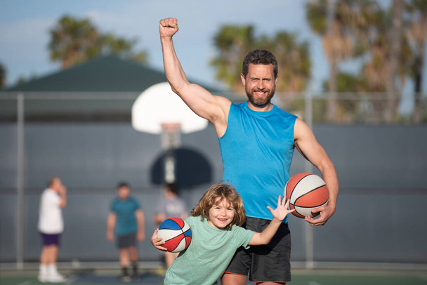 Father and son playing basketball. Excited family with a ball on the basketball court. - 写真・画像