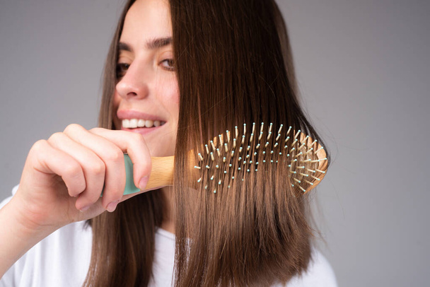 Close up woman combing hair. Hair Care. Beautiful brunette woman hairbrushing hair with hairbrush. Brushing healthy hair with comb. - Zdjęcie, obraz