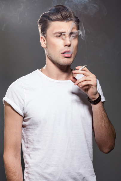 Handsome young man smoking cigarette - Fotó, kép