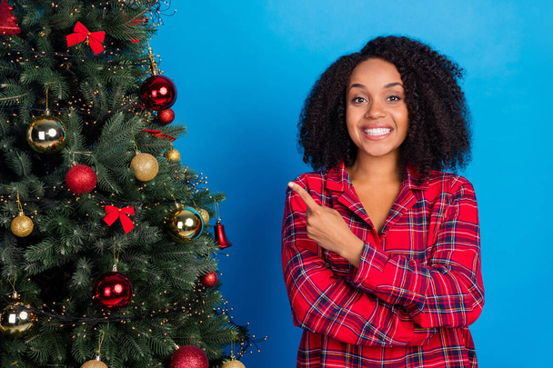 Photo of funny millennial brunette lady point tree wear red sleepwear isolated on blue color background - Foto, immagini