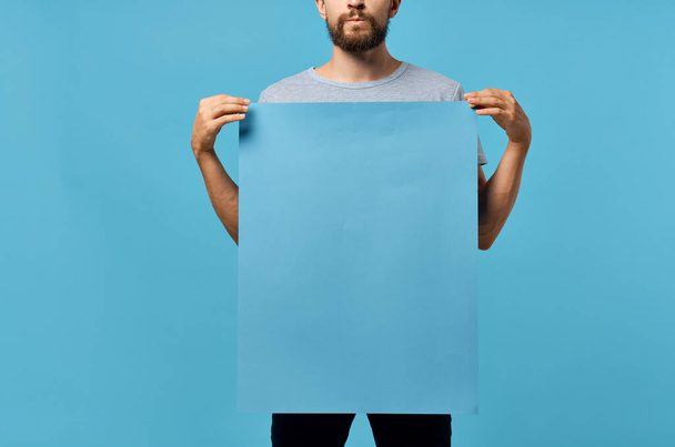 Cheerful man holding a mockup poster discount blue background - Foto, immagini