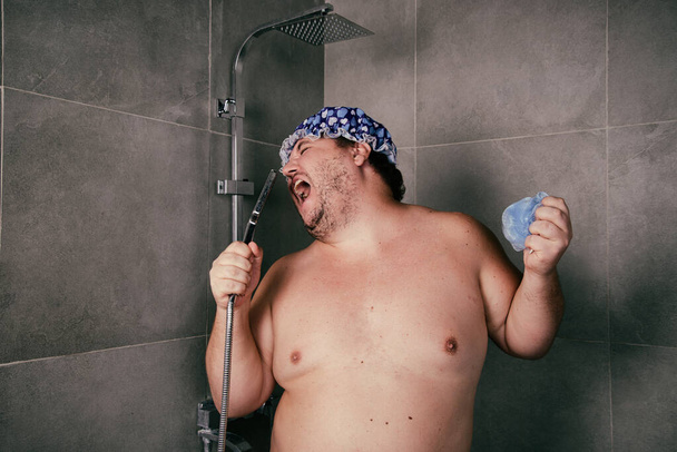 Смішний товстий чоловік миє в душі
. - Фото, зображення