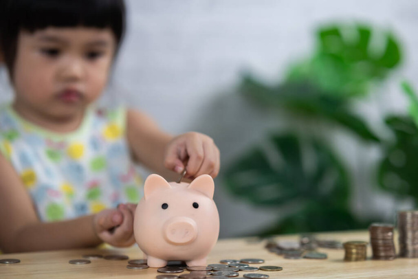 carino asia baby girl goccia monete in salvadanaio, concetto di risparmio. - Foto, immagini