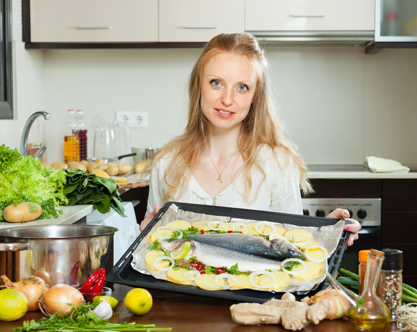 Woman cooking fish and potato in sheet pan - Foto, imagen