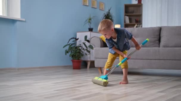 ajudando os pais, bonito menino ajuda os pais a limpar a casa e esfrega o chão na sala - Filmagem, Vídeo