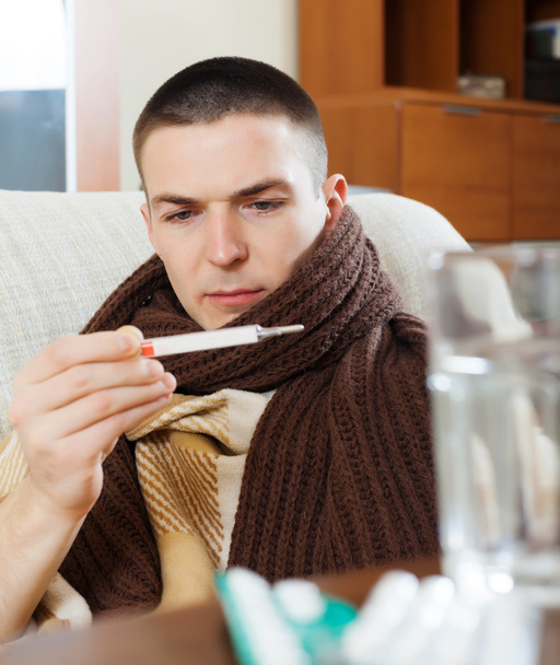 Sick man looking by thermometer - 写真・画像