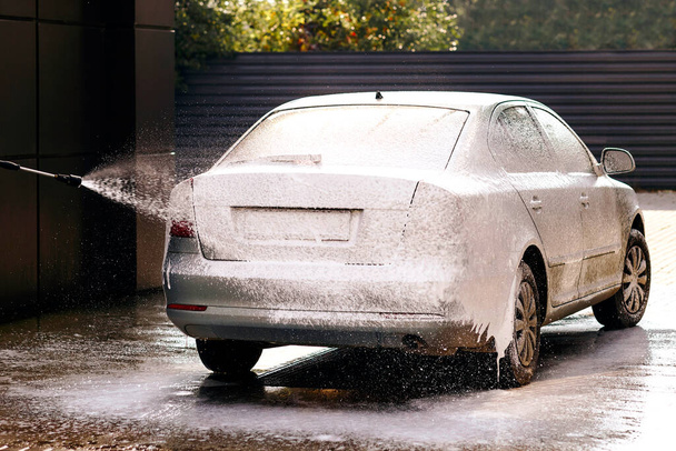 Self-service car wash. Applying detergent on the car. Car in the detergent is completely on the car washing - Foto, Imagen