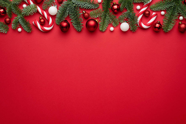 Fond rouge avec des décorations de Noël faites de branches de sapin et de boules de Noël. Blank avec un espace de copie pour le texte - Photo, image