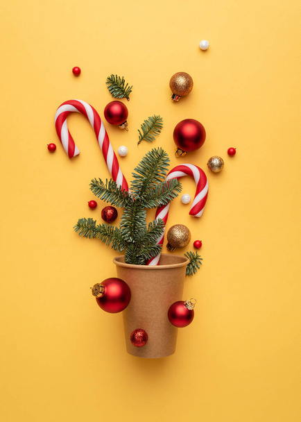 Tarjeta de Navidad con bastón de caramelo, bolas de Navidad y ramas de abeto sobre fondo amarillo - Foto, Imagen