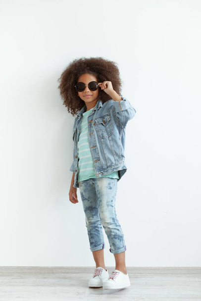 Stylish girl with beautiful curly hair wearing denim clothes and sunglasses - Фото, изображение