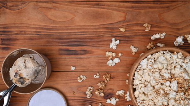 Bowl of popcorn and ice cream on wooden background. - Foto, imagen