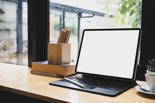 Computer-Tablet, Kaffeetasse und Bleistifthalter auf Holztisch. - Foto, Bild