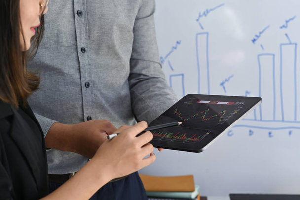 Business people analyzing graph of stock market on digital tablet together. - Φωτογραφία, εικόνα