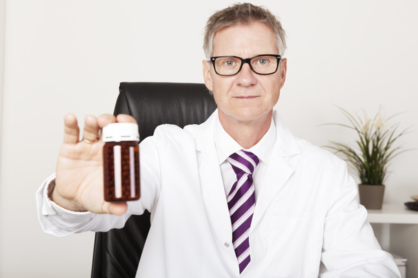 Pharmacist holding out a bottle of pills - 写真・画像