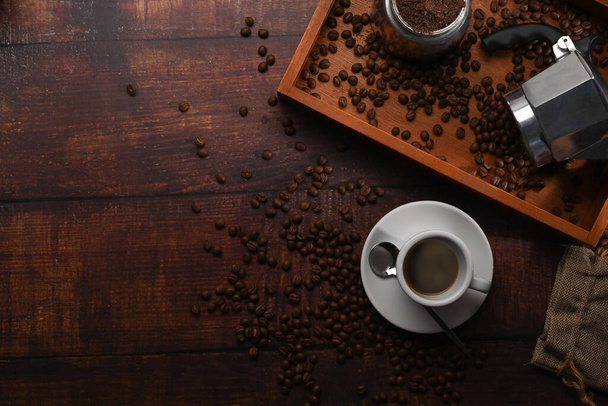 Above view cup of coffee and roasted coffee beans on wooden background. - Photo, Image