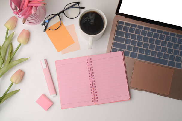 Spazio di lavoro donna con computer portatile, notebook, tazza di caffè e tulipani rosa. - Foto, immagini