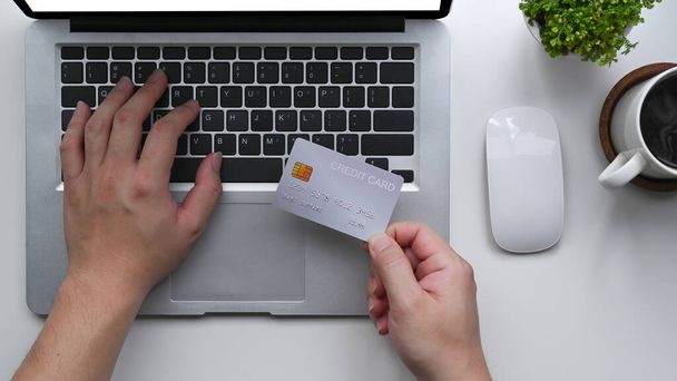 Чоловік тримає кредитну картку і використовує ноутбук для здійснення платежів онлайн
. - Фото, зображення