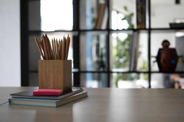 Pencil holder and books on wooden office desk. - Photo, Image