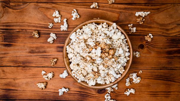 A bowl of popcorn on wooden background. - Foto, afbeelding