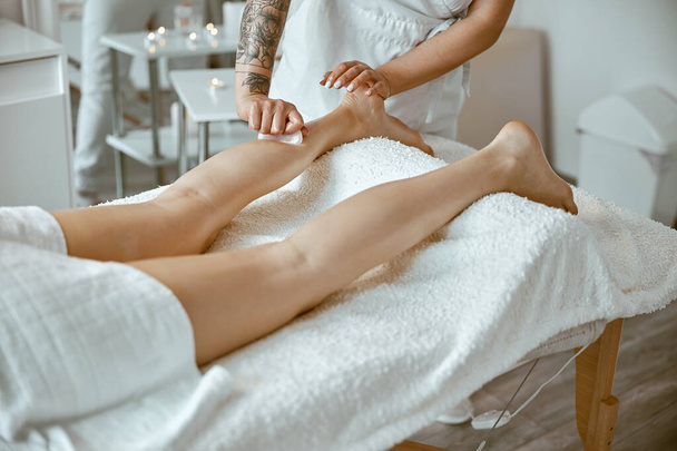 Mulher massagista está fazendo massagem profissional nas pernas no salão moderno - Foto, Imagem