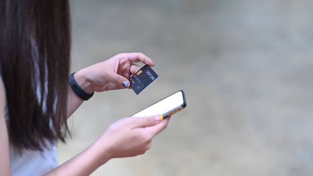 Manos de mujer sosteniendo tarjeta de crédito y utilizando el teléfono inteligente para la banca en línea o compras en línea. - Foto, imagen