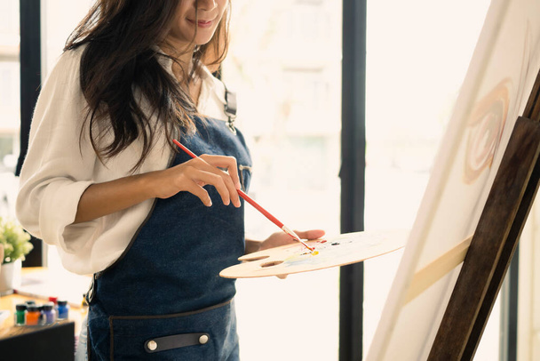 Femme artiste tenant le pinceau de peinture et la peinture de palette sur toile sur le lieu de travail créatif. - Photo, image