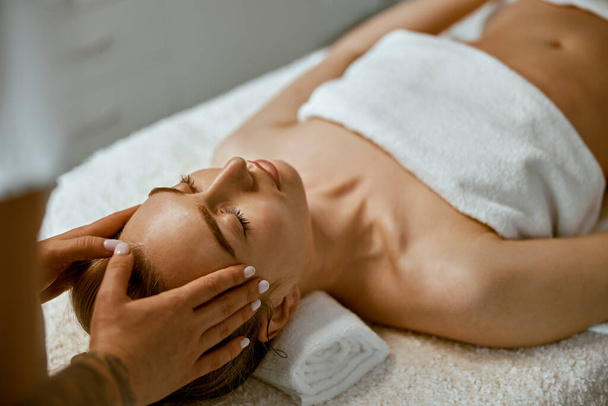 Терапевт робить обличчя розслабляючим масажем для молодої жінки в сучасному оздоровчому кабінеті
 - Фото, зображення