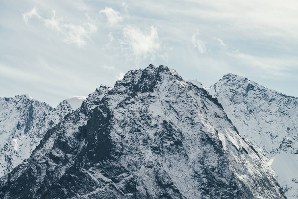 山頂からは雲が立ち込め、高い雪の山の壁を望むことができます。大きな雪でアルパインの風景は、太陽の下で鋭い頂点で山を覆った。太陽の光で白い雪の点のピーク. - 写真・画像