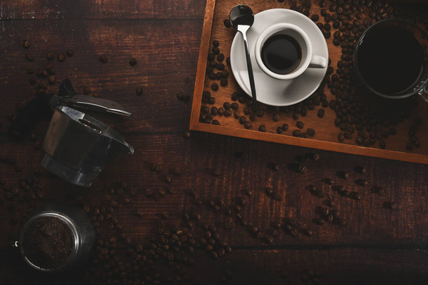 Above view roasted coffee beans and moka pot coffee maker on wooden background. - Photo, Image