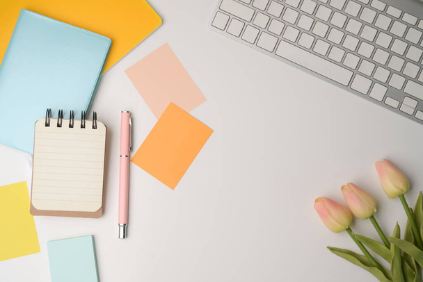 A fenti nézet színes ragacsos jegyzetek, notebook és rózsaszín tulipán fehér asztalon. - Fotó, kép