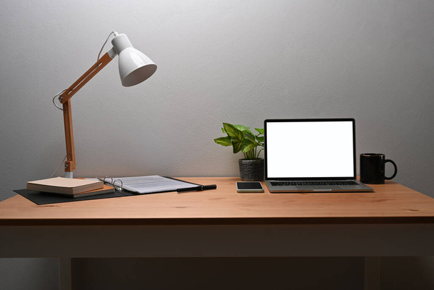 Ноутбук, кофейная чашка, чехол и лампа на деревянном столе. - Фото, изображение