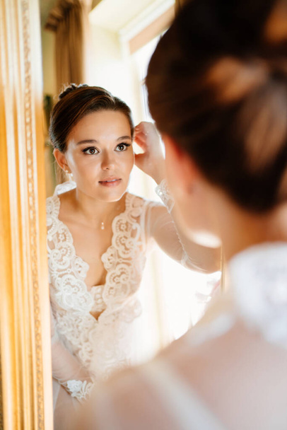 a beautiful young woman in a lace robe looks at her reflection in the mirror. - Φωτογραφία, εικόνα