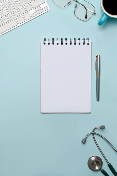 Notebook, stetoskop, brýle a šálek kávy na modrém pozadí. - Fotografie, Obrázek