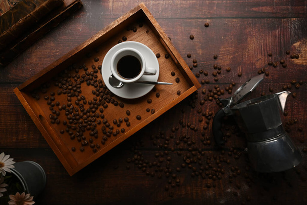 Oberseite Kaffeetasse mit gerösteten Kaffeebohnen und Mokkakanne über rustikalem Holzhintergrund. - Foto, Bild