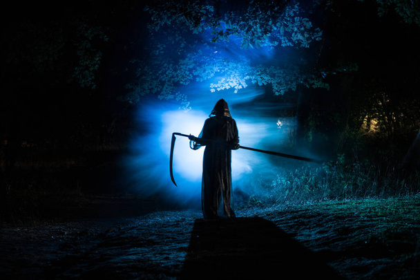 Karanlık sisli ormanda tırplarla ölüm. Ormanda azrail tutan kadın korku hayalet, cadılar bayramı kavramı - Fotoğraf, Görsel