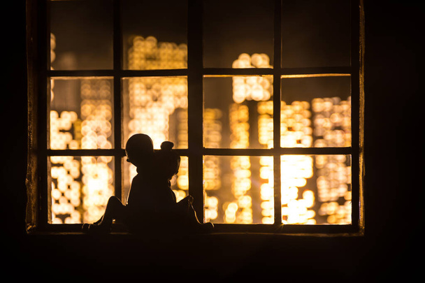 Beautiful view of a miniature city at night from window of dollhouse. Romantic couple at window. Artwork table decoration with handmade realistic dollhouse. Selective focus. - Photo, Image