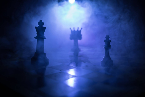 チェスボード上の美しいクラウンミニチュア。チェスボードゲームのビジネスアイデアと競争と戦略のアイデアの概念。煙と霧の暗い背景にチェスの数字。選択的焦点 - 写真・画像