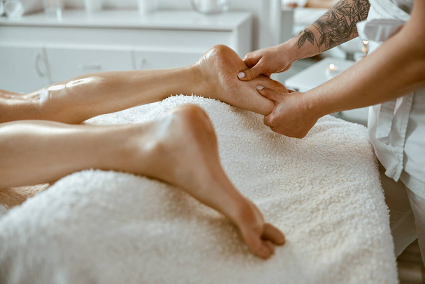 Professional caucasian specialist is doing leg message at modern minimalistic salon - Фото, изображение